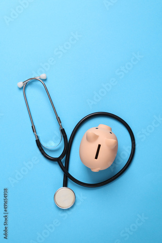 Piggy bank with stethoscope on blue background. Top view