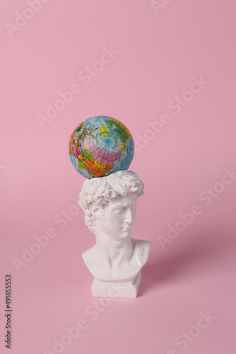 Antique David bust with globe on pink background. Conceptual pop. Minimal still life. Creative travel layout