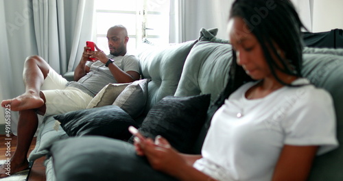 People at home looking at their cellphones. African american father and teen daughter using smartphone
