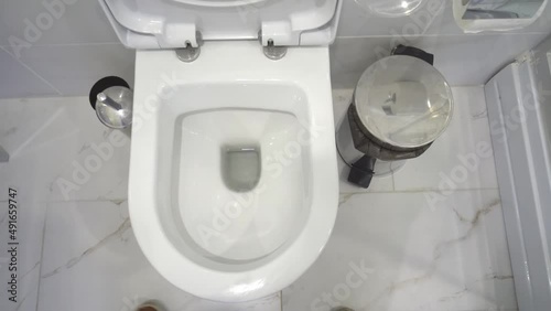 man is standing in modern toilet, and pissing in first person. stream of urine flies straight into hole of toilet. He does rim of toilet little. Modern renovation of toilet room. photo