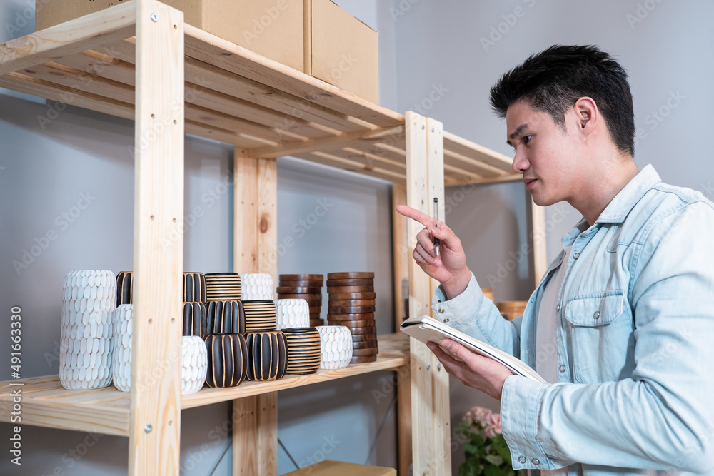 Asian young man talk with customer on phone to check vase goods order. Asian young man talk with customer on phone to check vase goods order.