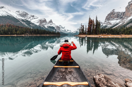 Fototapete Male traveler in winter coat canoeing in Spirit Island on Maligne Lake at Jasper