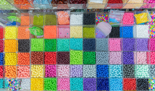 Beads are arranged and sorted by color. Background of colorful bright beads in boxes, set for needlework. High quality photo © Avi