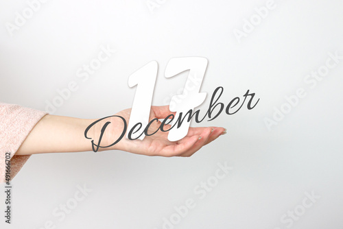 December 17th. Day 17 of month, Calendar date. Calendar Date floating over female hand on grey background. Winter month, day of the year concept.