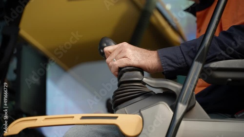 A man inside an excavator cabin moving the controls.