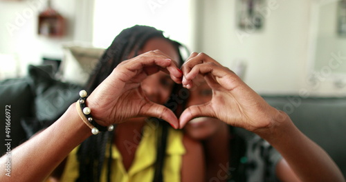 Mixed race mother and teen daughter making heart symbol with hands