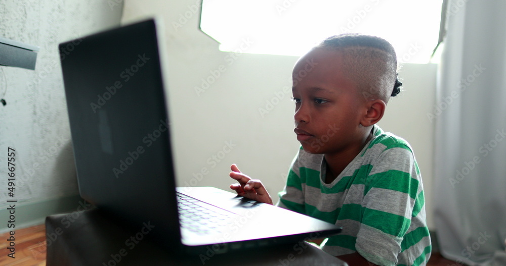 Mixed race little boy browsing internet on laptop. Child using computer Mixed race little boy browsing internet on laptop. Child using computer