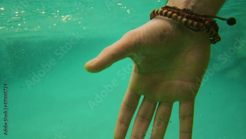 A man pulling a young woman out of the water. Slow motion