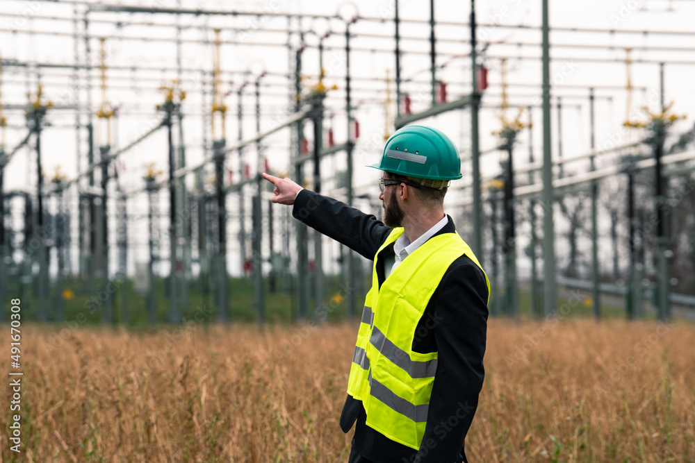 custom made wallpaper toronto digitalElectric engineer wearing helmet suit and safety vest at bad weather pointing at substation