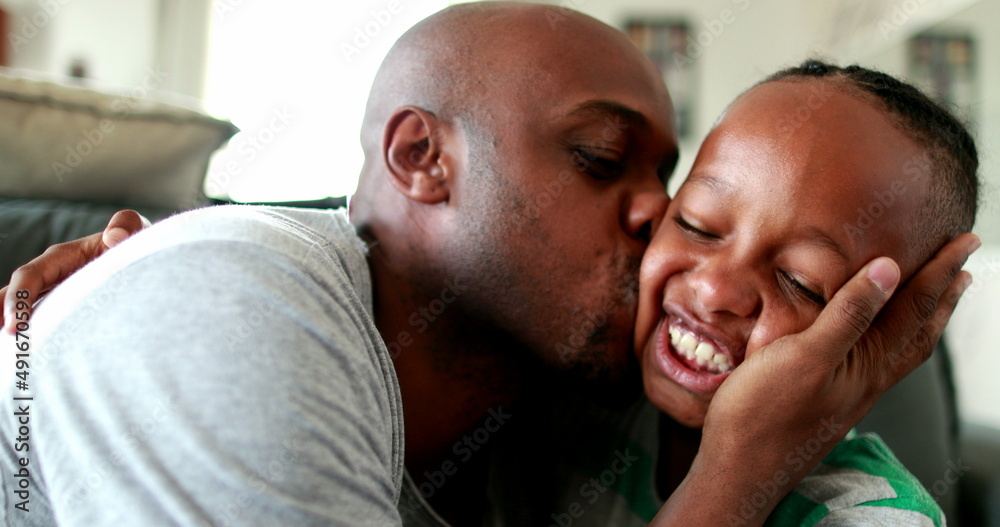 Father and son love and affection. Parent kissing and hugging little boy child. Mixed race African ethnicity