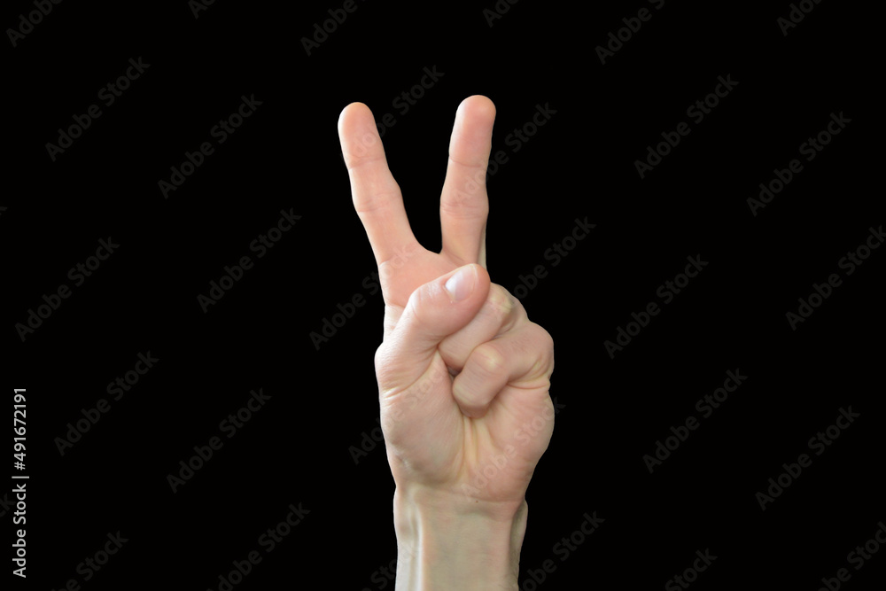 Male hand showing gesture of Victoria. Two fingers raised Up on black background. Peace and victory. Male hand showing gesture of Victoria. Two fingers raised Up on black background. Peace and victory.