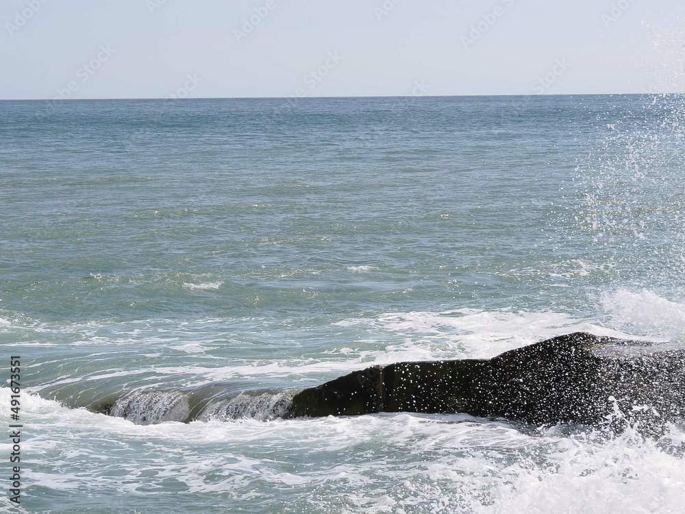 Fototapeta premium waves splashing and water spray over the rocks in the sea
