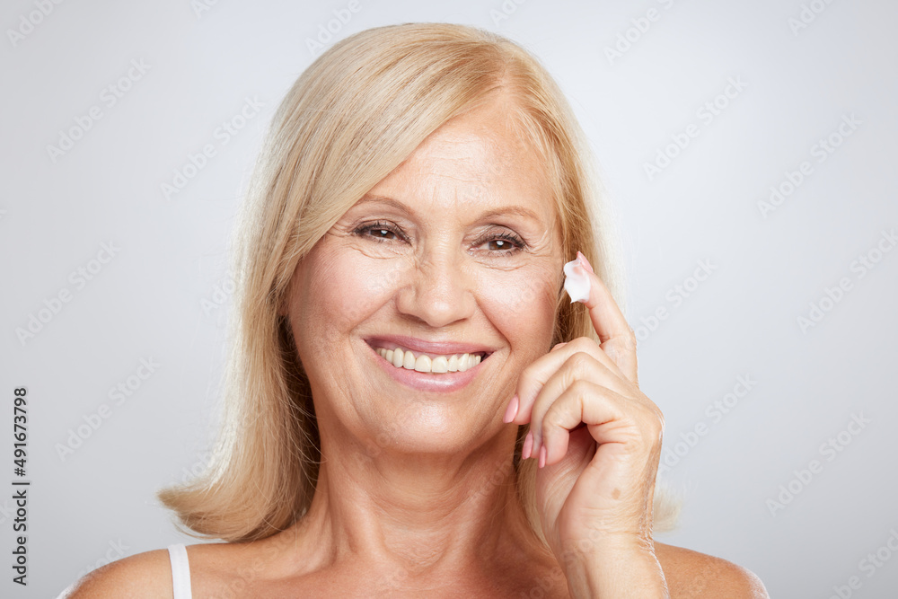 An attractive blond senior woman putting anti-age creme. Beauty photography An attractive blond senior woman putting anti-age creme. Beauty photography