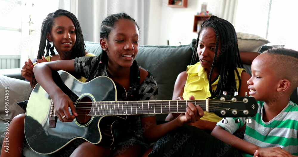 Casual black African family bonding thogether through music guitar. Daughter playing musical instrument
