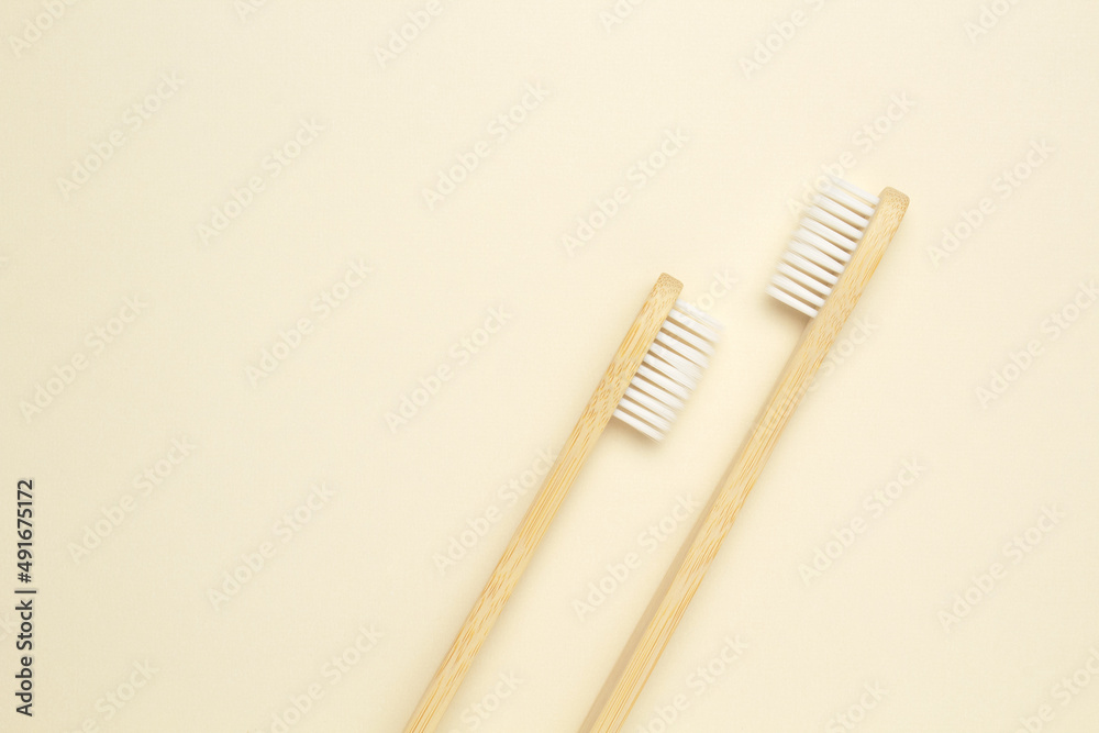 Two wooden bamboo eco friendly toothbrushes on beige background. Dental care and zero waste concept. Flat lay, top view, copy space Two wooden bamboo eco friendly toothbrushes on beige background. Dental care and zero waste concept. Flat lay, top view, copy space