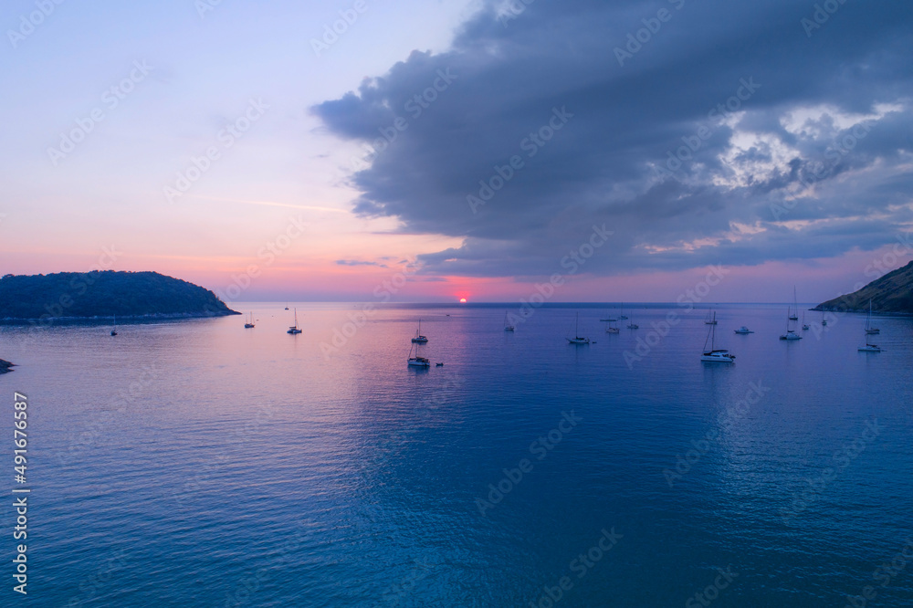 Fototapeta premium Colorful sunset above the sea surface with sail boats Aerial view sea in Phuket sea Reflected sun amazing light on a water surface Sunset over ocean Seascape Summer and travel vacation concept