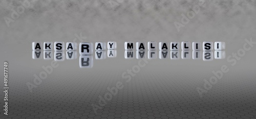 aksaray malaklisi word or concept represented by black and white letter cubes on a grey horizon background stretching to infinity photo