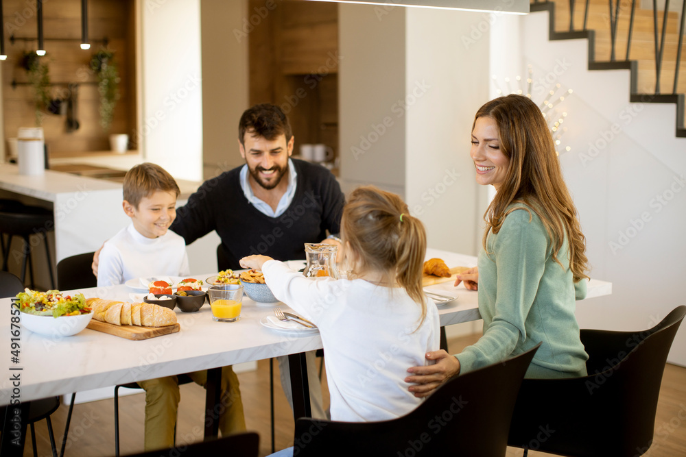 Young happy family talking while having breakfast at dining table Young happy family talking while having breakfast at dining table