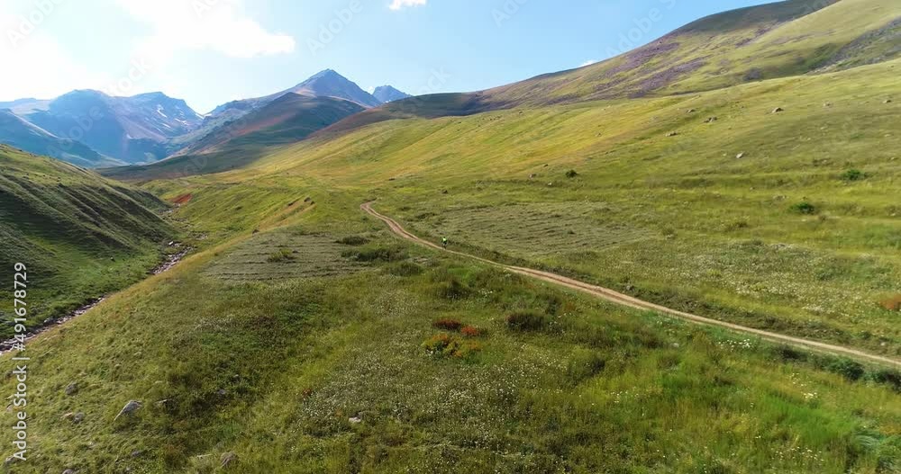 Cyclist riding in the Mountains. Beautiful mountain view from above. aerial drone footage. Bird's eye view. Alpine Green valley. Off-road bicycle. Rocks. Caucasus. The Alps. Nature. Tourism. Cyclist riding in the Mountains. Beautiful mountain view from above. aerial drone footage. Bird's eye view. Alpine Green valley. Off-road bicycle. Rocks. Caucasus. The Alps. Nature. Tourism.