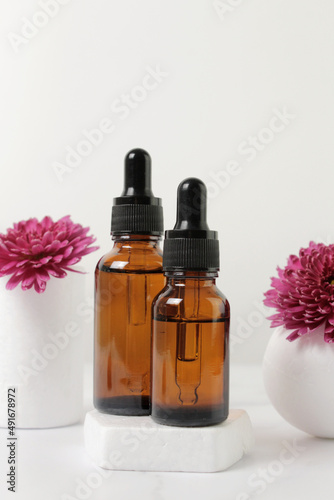 A mock-up of an empty glass dropper bottle made of brown glass stands on a white podium and a white background. Skin care serum  banner or template. The concept of a natural cosmetic product.Copyspace