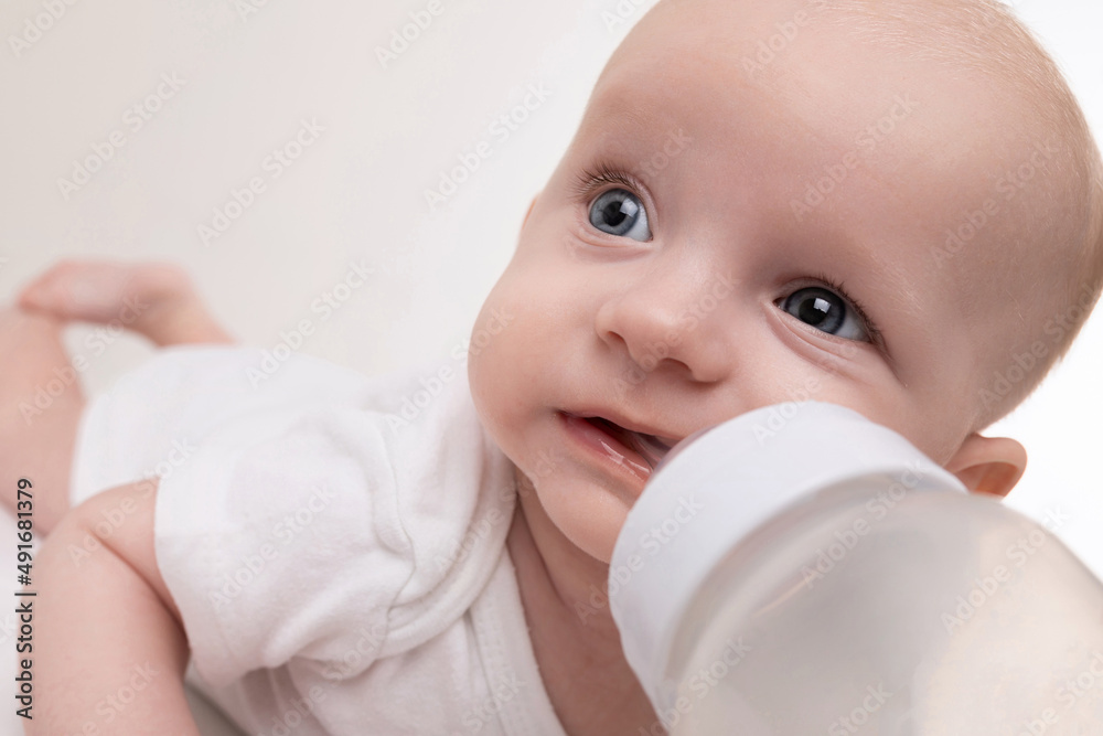 newborn baby drinks milk from a bottle on a white background newborn baby drinks milk from a bottle on a white background