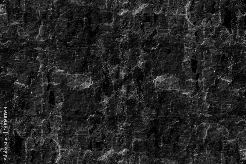 Abandoned old rugged surface of a dark stone wall for texture background