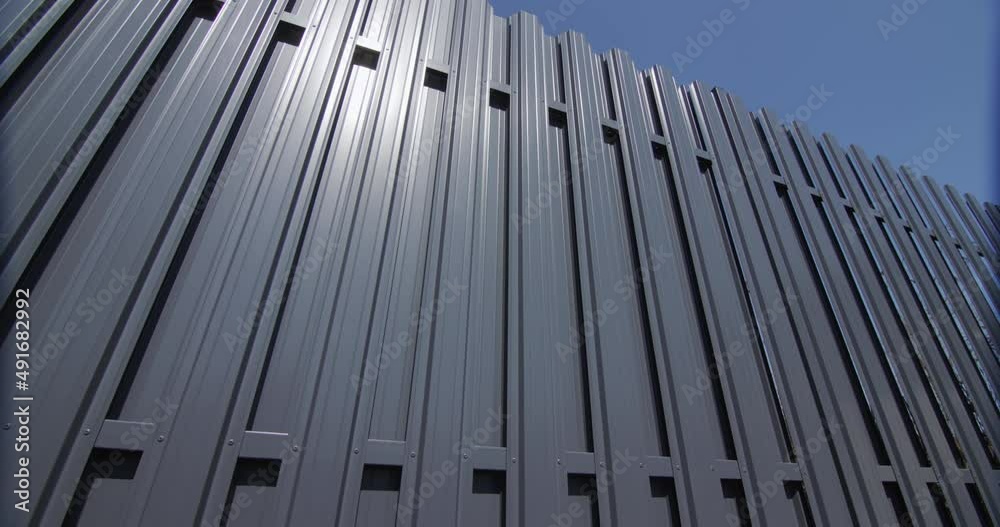A fence made of grey metal stripes. Against the blue sky A fence made of grey metal stripes. Against the blue sky