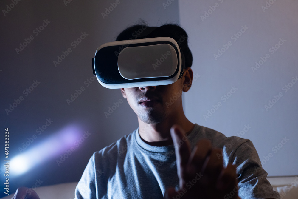 Young man wearing the virtual reality goggles and hand up to touch something