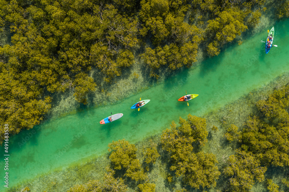 © AmazingAerialAgency - Aerial view of people doing kayak in a small river off Abu Dhabi, United Arab Emirates.