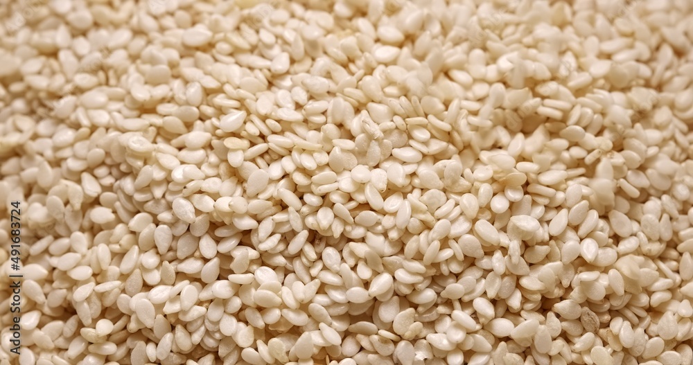 Closeup photo of natural dried white sesame seeds flowing