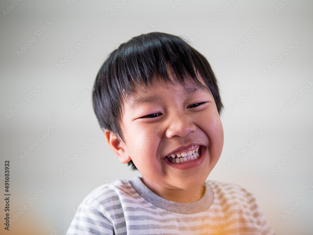 Asian cute child boy smiling and laughing with whitening teeth at home isolated white background. Kid enjoying in funny shot in relaxing day. Concept of healthy lifestyle, happy expression. Asian cute child boy smiling and laughing with whitening teeth at home isolated white background. Kid enjoying in funny shot in relaxing day. Concept of healthy lifestyle, happy expression.