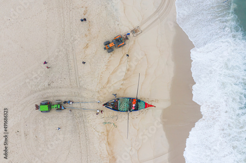 Aerial view of people along the shoreline prating the Arte Xavega, a Portuguese traditional fishing technique in Torreira, Portugal. photo