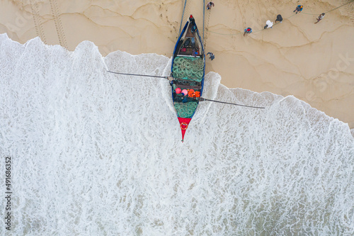 Aerial view of people along the shoreline prating the Arte Xavega, a Portuguese traditional fishing technique in Torreira, Portugal. photo