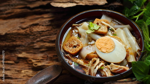 Chinese roll noodle soup with chicken on wooden background