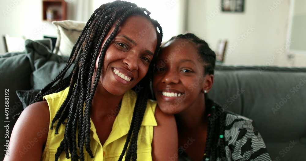 African mother and teen daughter smiling at camera