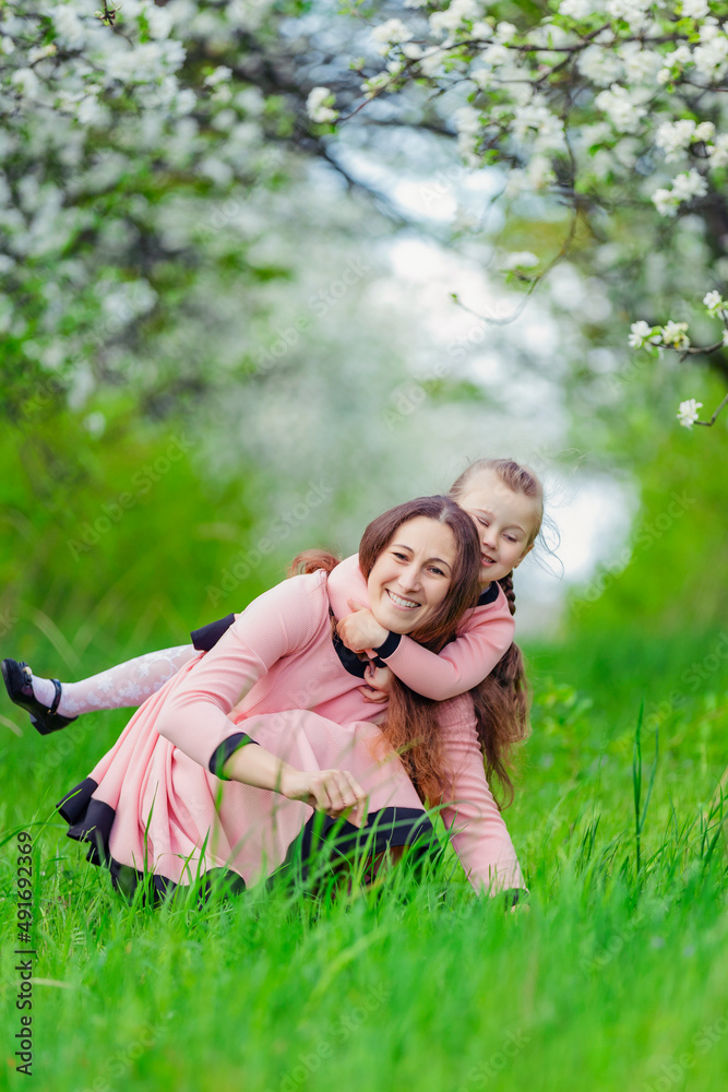 mother and daughter hugging against the backdrop of flowering trees mother and daughter hugging against the backdrop of flowering trees