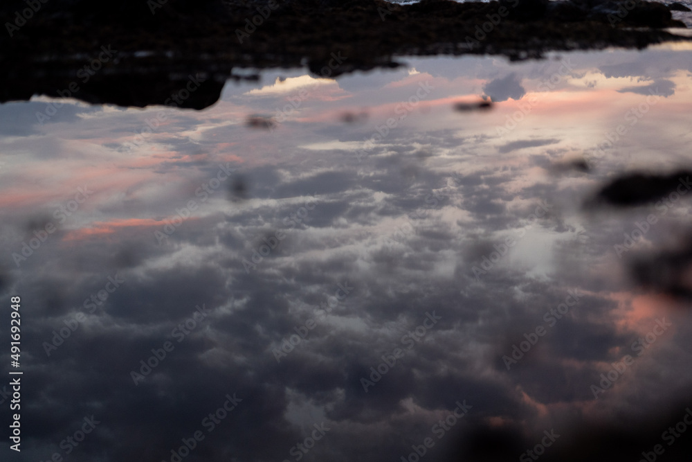 Sunset sky reflecting on water on coast of island Sunset sky reflecting on water on coast of island