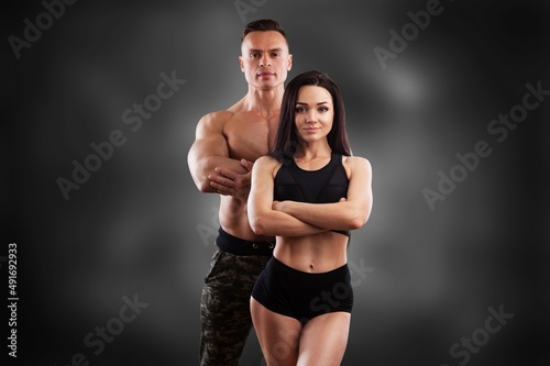 Sporty couple showing muscles. Muscular man and woman posing