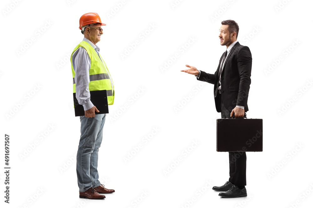 Full length profile shot of a businessman talking to a male engineer with a safety vest and hardhat Full length profile shot of a businessman talking to a male engineer with a safety vest and hardhat
