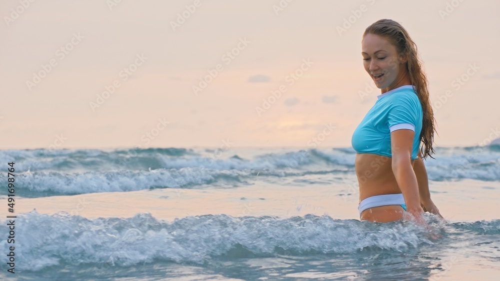 SLOW MOTION GLOW MIST GOLD SUNSET CINEMATIC VIEW: Attractive woman standing on water sea. Girl stand in turquoise swimsuit. Freedom paradise holiday vacation summer beach, seaside landscape concept SLOW MOTION GLOW MIST GOLD SUNSET CINEMATIC VIEW: Attractive woman standing on water sea. Girl stand in turquoise swimsuit. Freedom paradise holiday vacation summer beach, seaside landscape concept