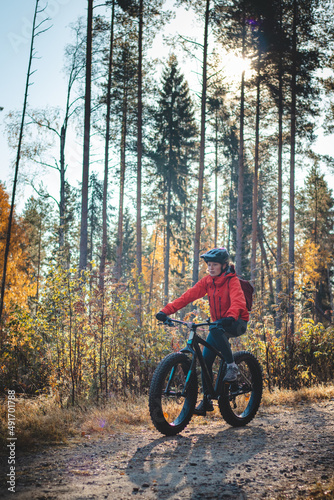 Young likeable lady with a lovely realistic smile while recreationally sporting. Cyclist riding fat bike in Finnish wild nature. Vuokatti area. Cycling clothing and helmet. Cycling