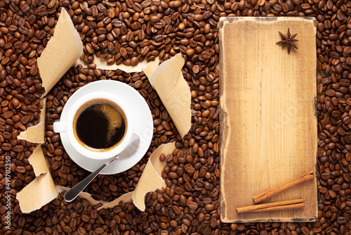 Cup of coffee and beans in torn paper. Coffee ingredients with espresso