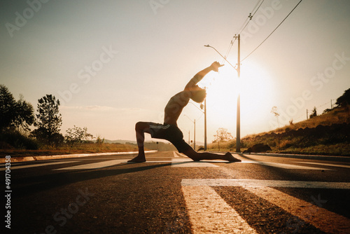 Young man doing yoga asana exercise in the middle of the road. 