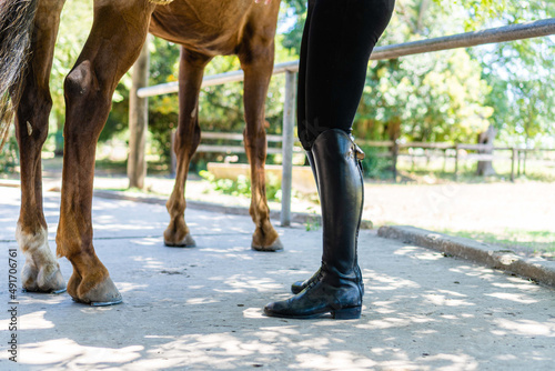 unrecognizable woman wearing English boots or riding boots next to her horse