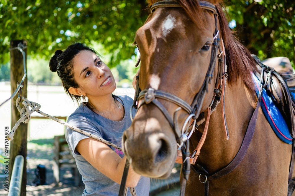 Obraz premium young latina woman smiling next to her silla argentina horse