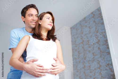 Aspirations for their baby. Young man holding his girlfriends pregnant belly as they look on in thought.