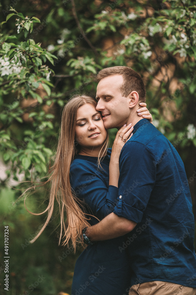 Handsome young guy with a girl stand in the spring garden. Romantic couple are walking in the park. Happy relationship concept Handsome young guy with a girl stand in the spring garden. Romantic couple are walking in the park. Happy relationship concept