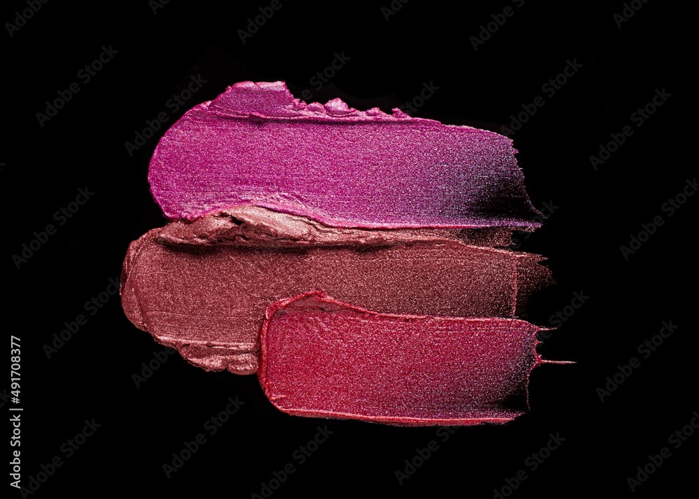 Fototapeta premium Lipstick abstract strokes smudges background texture multi colored red pink fuchsia chocolat glitter shimmer isolated on black background
