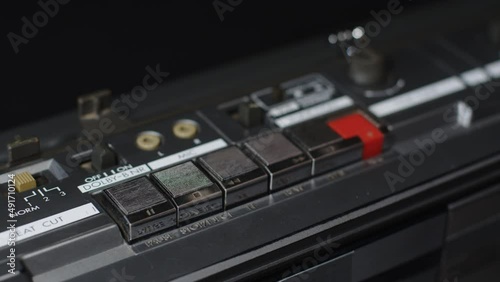 Close-up of a finger that presses the stop button on an old silver shiny cassette recorder