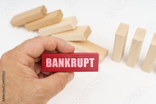 In the foreground, a hand with a red wooden block and the inscription - Bankrupt